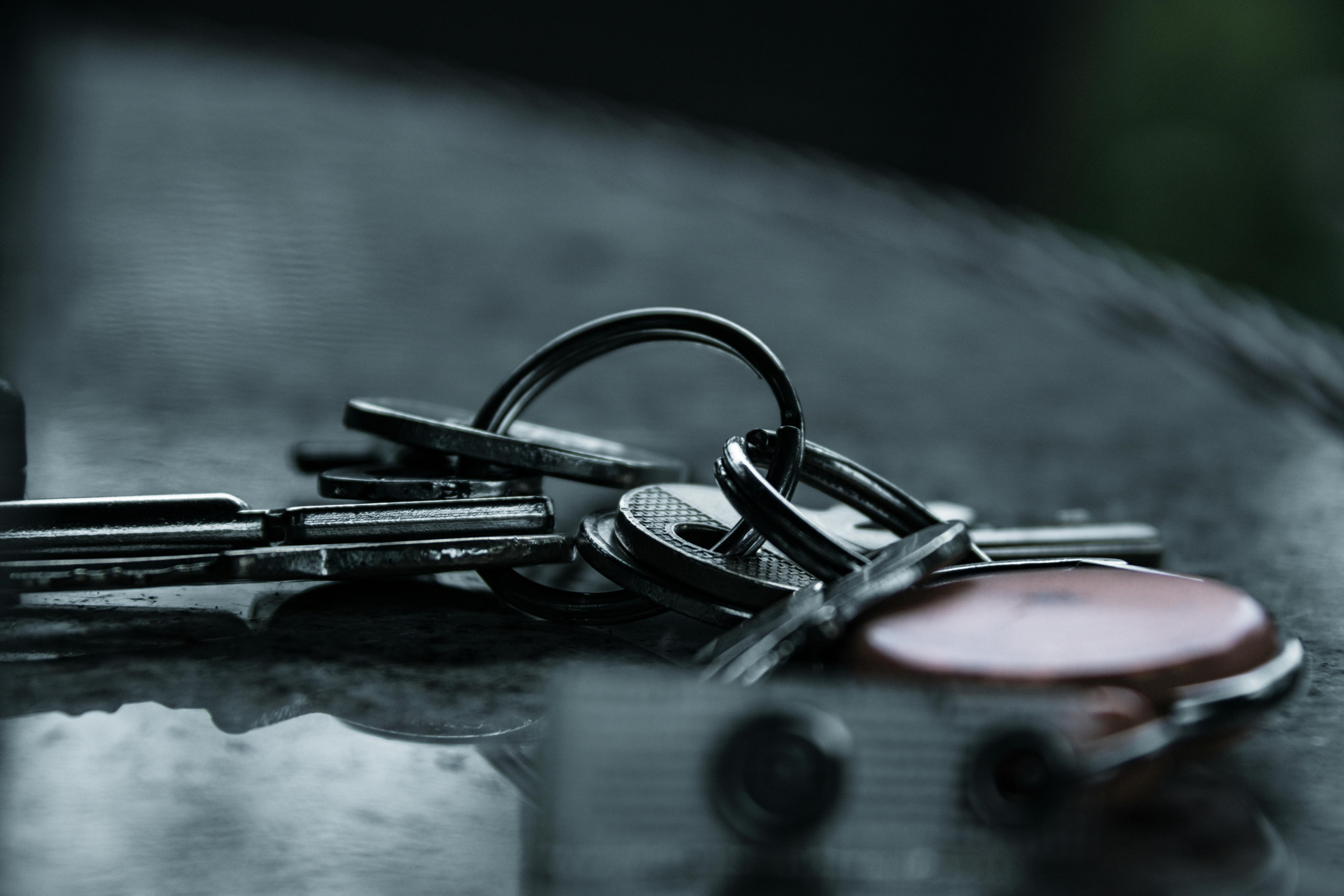 A dramatic close-up of metal keys on a reflective surface, capturing a moody and conceptual still life.